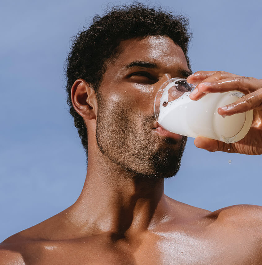 Man drinking from a glass against a clear blue sky