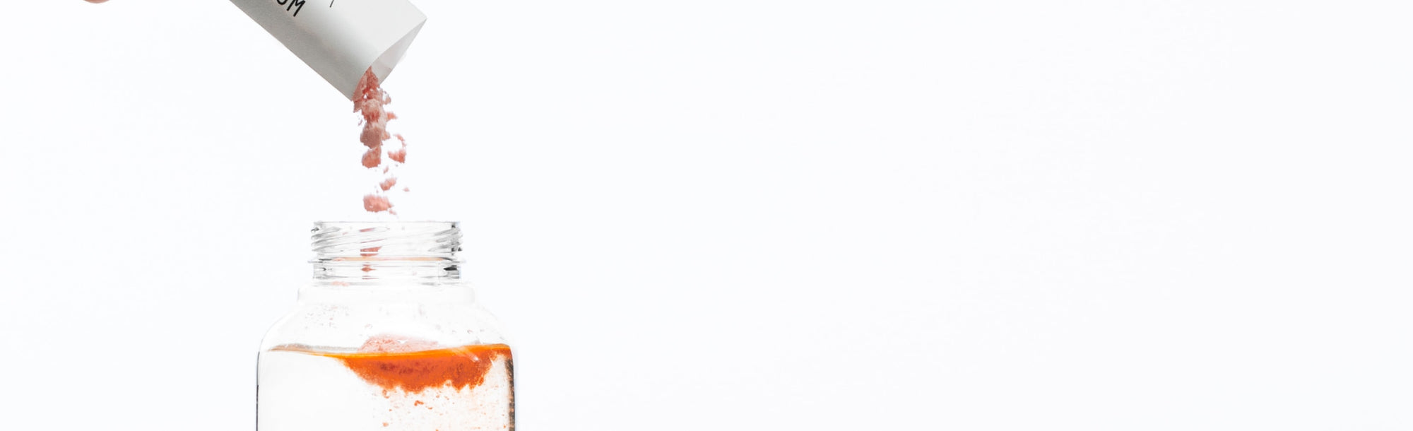 White background with a clear bottle and ARMRA immune revival blood orange product being poured in